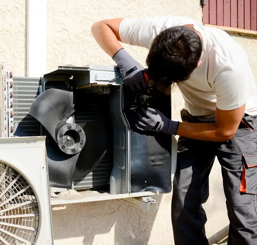 A man working on an air conditioner outside.