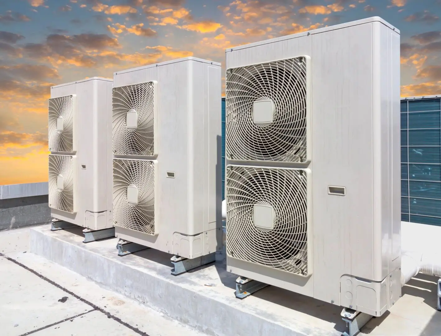 A row of air conditioners sitting on top of concrete.